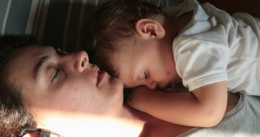 Anne bebeğiyle yatıyor. Dürüst, yorgun ve yorgun ebeveyn uykuda.