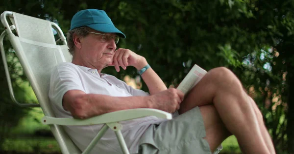 Senior Man Leaning Reading Book Casually — Stockfoto