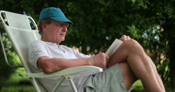 Senior Man Leaning Reading Book Casually — Zdjęcie stockowe