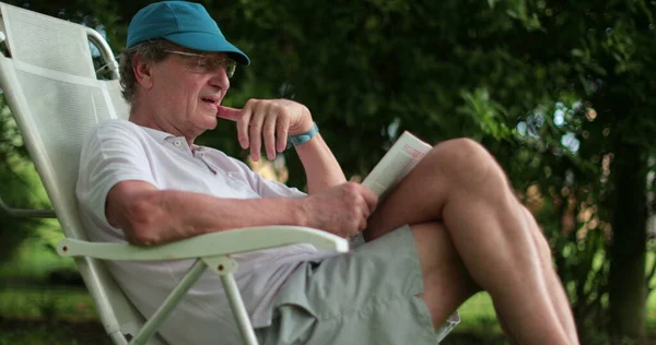 Senior Man Leaning Reading Book Casually — Stock Photo, Image
