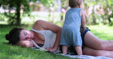 Bitkin düşmüş anne çimenlerde yatıyor.