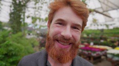 Arka planda yeşil bir çevreyle kameraya gülümseyen mutlu kızıl saçlı genç bir adamın yakın çekim yüzü. 30 'lu yaşlarda beyaz sakallı bir erkek portresi.