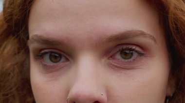Makro yakın plan kızıl saçlı kadın kameraya ciddi bir ifadeyle bakıyor. 30 'ların kadın milenyum insan gözü.