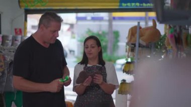 Kadın Sahibi Pet Shop müşteriye dükkandan köpek oyuncakları seçmesinde yardım ediyor.