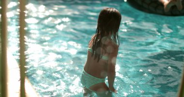 Havuzdaki çocuk suya girmekten korkuyor.