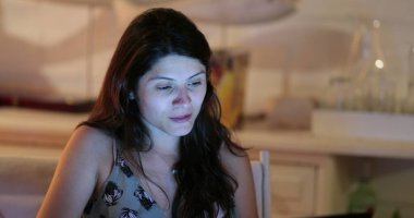 Çekici bir kadın geceleyin bilgisayar ekranının önünde internete göz atıyor.