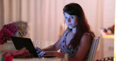 Bir kadının kamerayı fark edip kameramandan saklandığı komik bir an. Bilgisayarın önünde gülümseyen mutlu kadın.