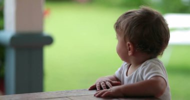 Baby standing holding furniture upset. Angry toddler infant complaining mood