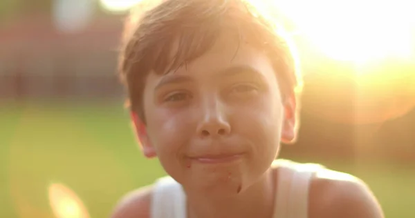 黄金の時間の日没時に外のカメラに笑みを浮かべてハンサムな少年の子供 — ストック写真