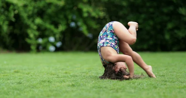 幸せな子供の女の子は芝生の上で転がり 転げ落ち 子供は宙返りをする — ストック写真