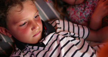 Geceleri elinde tablet cihazıyla ekrana bakan çocuk içeriği çevrimiçi izliyor