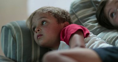 İki erkek kardeş ve kız kardeş, geceleri kanepede uzanmış film izliyorlar.