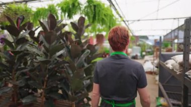 Bahçıvanlık malzemeleri satan dükkanda önlük giyen erkek işçinin arkası. Çiçekçide adanın içinden geçen kişi