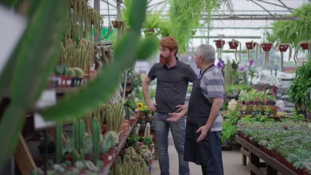 高级职员协助年轻顾客在园艺花店内购买植物 — 图库视频影像
