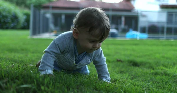 Infant baby crawling outside in home backyard garden grass