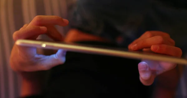 stock image Kid holding tablet device at night touching screen playing game, seen from above