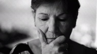 Derin düşüncelere dalmış, tek renkli siyah beyaz çeneli dramatik yaşlı kadın.