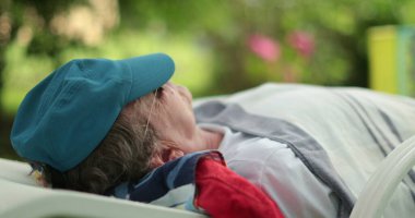Older man napping outdoors. Candid senior person sleeping