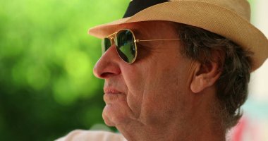 Pensive older man wearing sunglasses and hat. Thoughtful senior person thinking