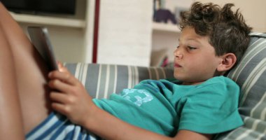 Genç bir çocuk tablet ekran cihazına bakıyor. Video oyunu oynayan çocuk