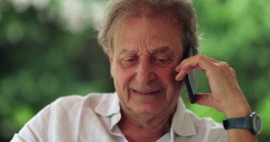 Happy older man speaking with friend on cellphone