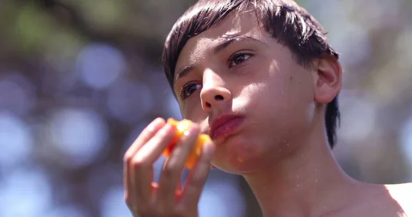 屋外で果物を食べる小児 思慮深い子供が桃を噛む — ストック写真