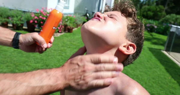 外の子供の体の皮膚に日焼け止めをスプレー — ストック写真