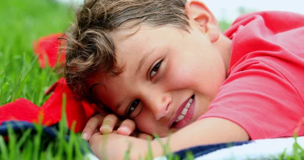 一个英俊的小男孩对着放在外面草地上的相机笑着 — 图库照片