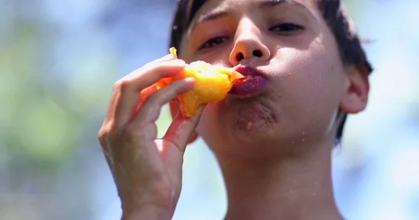 外で桃を食べる子供 健康的なフルーツスナックを一口飲んでいる子供の男の子 — ストック写真