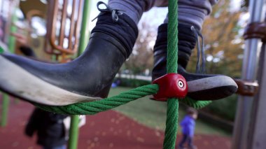 Çocuk parkında oynayan aktif küçük bir çocuk. Beyaz erkek çocuk dışarıda idman yapıyor. Metal çubuğu tutuyor.