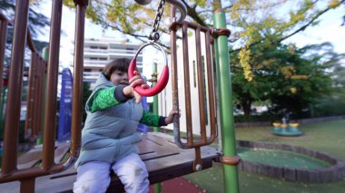 Aktif bir çocuk dışarıda metal bir şebekeyi tutuyor. Dışarıda egzersiz yapan mutlu beyaz erkek çocuk. Çocukluk yaşam tarzı gelişimi kavramı