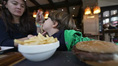 Anne, restoranda oturan çocuğa makarna yediriyor. Yaşam tarzı anne ve çocuk yemek yiyor.