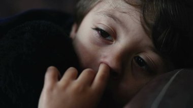 Dalgın küçük çocuk burnunu karıştırıyor. Yakından erkek, düşünceli çocuk burnunu karıştırıyor.