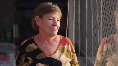 Yalnız, yaşlı bir kadın derin düşüncelere dalmış, pencerenin kenarında dikiliyor. Yalnızlıktan muzdarip yaşlı insan düşüncelere dalmış.