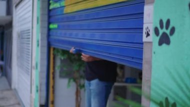 Şehir kaldırımında dükkan önü açan bir adam. Sokağın ortasındaki atölyede slayt yapan kişi