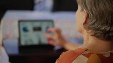 Tablet modern cihazda internete göz atan yaşlı bir insanın arkası. Son sınıf öğrencisi bir kadın çevrimiçi dükkanda dolaşıyor.