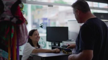 Erkek müşteri, Pet Shop 'un neşeli bayan girişimcisiyle küçük işletme tezgahında telefonla ödeme yapıyor. Bağlantısız cep telefonu ödemesi