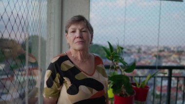 Ciddi bir yaşlı kadın ciddi bir ifadeyle apartmanın balkonunda dikiliyor. Otantik aile sahnesinde yaşlı bir kişinin portresi
