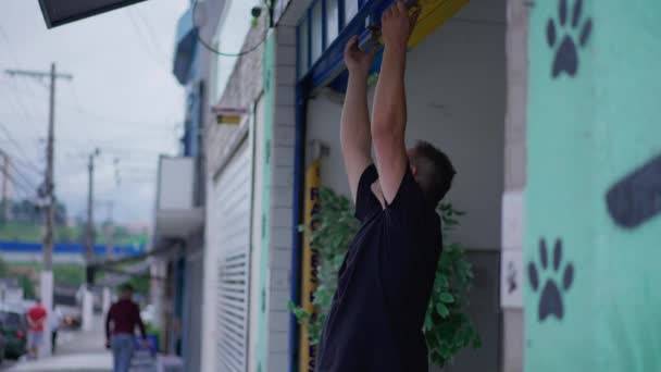 Person Die Örtliche Schaufenstergaragen Schließt Mann Rutscht Geschäftsfassade Auf Gehweg — Stockvideo
