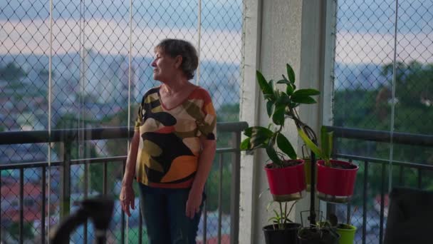 Femme Âgée Contemplative Debout Par Fenêtre Balcon Appartement Regardant Extérieur — Video