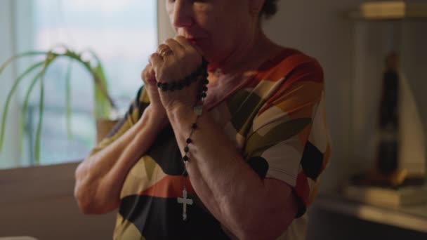 宗教的なカトリックの年上の女性は深く熟考して自宅でロザリオを祈っています 希望と信仰を持つ高齢者 — ストック動画