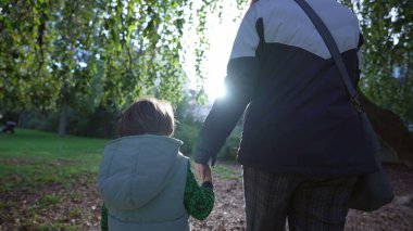 Güneşli sonbahar gününde parkta el ele tutuşan anne ve çocuk. Anne ve oğul el ele tutuştular. İki kişi. annelik yaşam tarzı