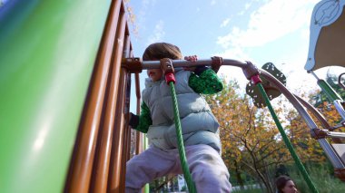 Küçük çocuk dışarıda antrenman yapıyor. Oyun alanındaki metal barda. Aktif Çocuk açık havada aktif. Çocukluk yaşam tarzı