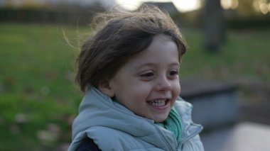 Aktif küçük bir çocuk ağır çekimde dışarı koşuyor. Dışarıda koşan ve gülen çocukların mutluluk konsepti.