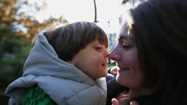 Mutlu anne ve çocuk Eskimo öpücüğü yapıyor. Burunları dışarıda, güneş ışığıyla parlıyor. Annelik yaşam tarzı konsepti