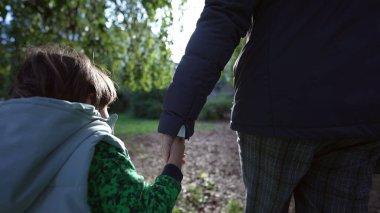 Güneşli sonbahar gününde parkta el ele tutuşan anne ve çocuk. Anne ve oğul el ele tutuştular. İki kişi. annelik yaşam tarzı