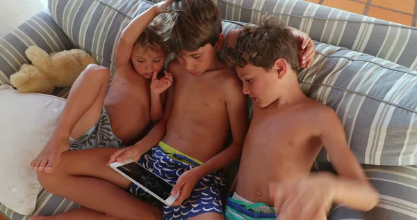 男孩们在平板电脑屏幕上在线观看内容 沙发上的孩子们拿着科技小玩意看电影 — 图库照片