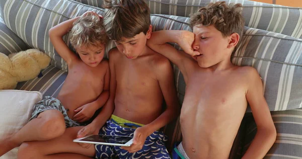 男孩们在平板电脑屏幕上在线观看内容 沙发上的孩子们拿着科技小玩意看电影 — 图库照片