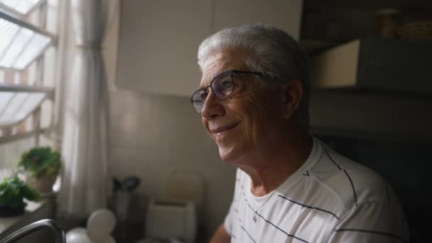 Ευτυχισμένος Ηλικιωμένος Άνδρας Κοιτάζει Έξω Από Παράθυρο Ακουμπώντας Στον Πάγκο — Αρχείο Βίντεο