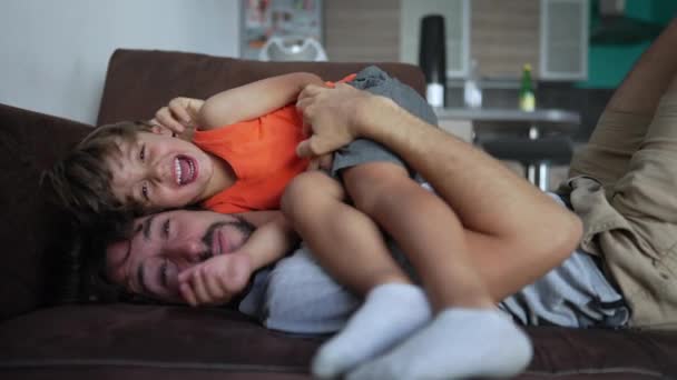 父亲和孩子躺在沙发上笑着 父母和小儿子的结合时刻 真正真实的家庭生活场景 — 图库视频影像
